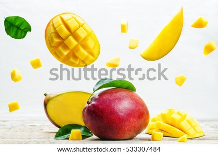 mango with flying slices on a white wood background. tinting. selective focus  Royalty-Free Stock Photo #533307484