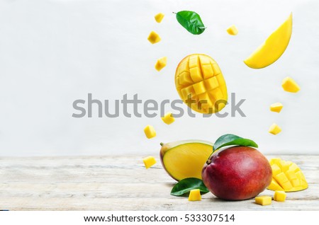 mango with flying slices on a white wood background. tinting. selective focus  Royalty-Free Stock Photo #533307514