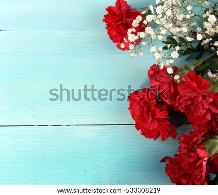 top to red Carnation flowers blue wood background