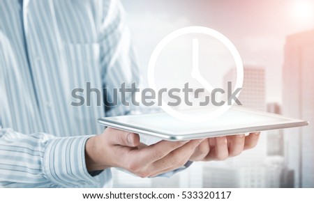 Hands of businessman holding tablet and clock icon on screen