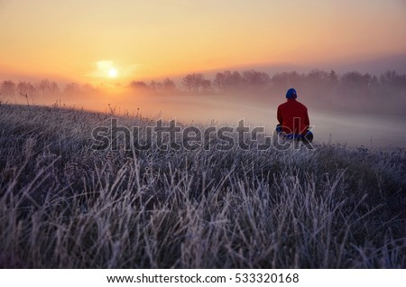 Young man standing in winter frozen nature and watching to the calm winter misty sunrise. Original wallpaper or background from nature - thinking concept, photo full of freedom, beautiful landscape