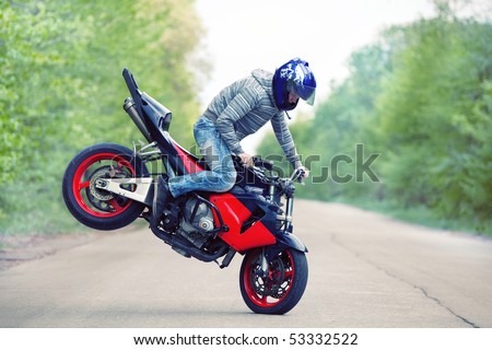 Stunt rider making stoppie on the summer forest background Royalty-Free Stock Photo #53332522