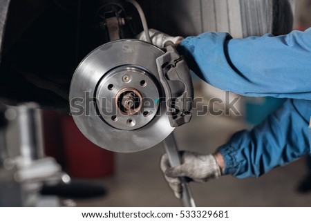 change the old drive to the Brand new brake disc on car in a garage. Auto mechanic repairing . Royalty-Free Stock Photo #533329681