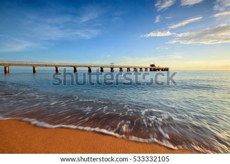 Beautiful sunset or dusk sky over the long jetty at seascape. Motion blur on foreground or wave due to slow shutter speed shot. Composition of nature.