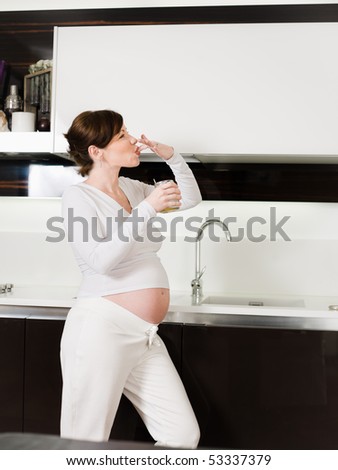 portrait of italian 6 months pregnant woman eating sweet food in kitchen. Vertical shape, copy space