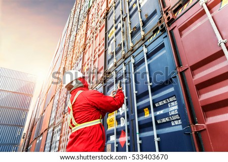 Foreman control loading Containers box from Cargo freight ship for import export. Royalty-Free Stock Photo #533403670