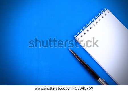 Notebook and ball pen on a blue background.