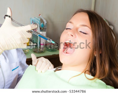 dentist hand holding a syringe, making a numb shot for woman patient, horizontal shot