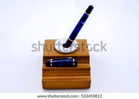 Fountain pen and inkwell over white background
