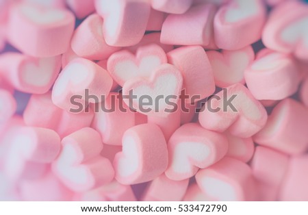 Pink marshmallow in heart shape stacked on blue wood table with copy space. Sweet candy for love theme on Valentine concept in vintage style. Pastel color dessert for background or wallpaper decor.
