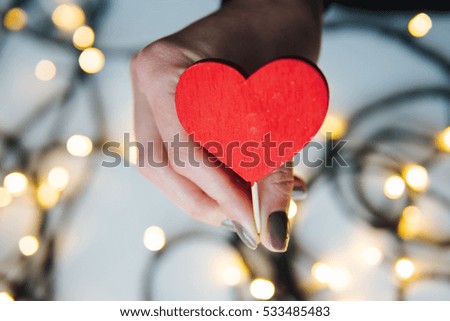 girl holding a red heart in the hands on the background of garlands