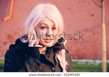 Young woman in the pink wig talking on mobile phone on the street Royalty-Free Stock Photo #533493181