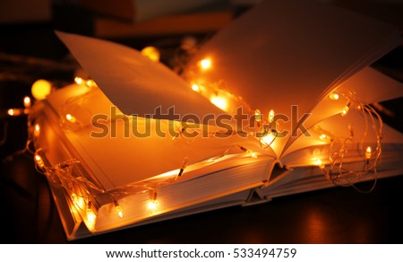 Closeup view of open books and beautiful garland on table