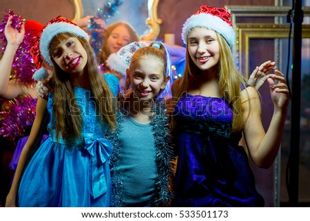 Group of cheerful young girls celebrating Christmas near the Christmas tree with lights