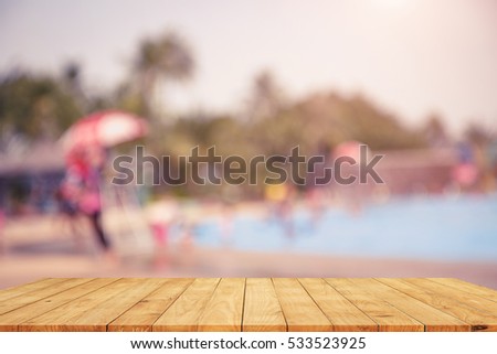 blurred Vintage tone picture of Empty wooden table on swimming pool background , rest and relax concept