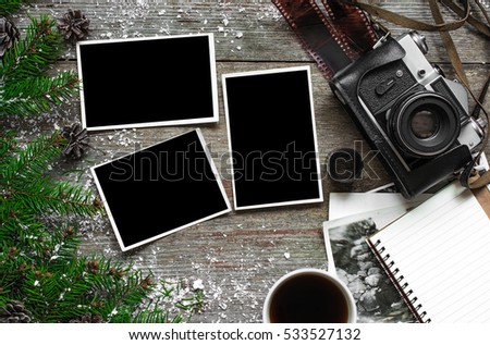 Vintage photo camera on christmas wooden background with blank photo frames, notebook and cup of coffee. top view. flat lay
