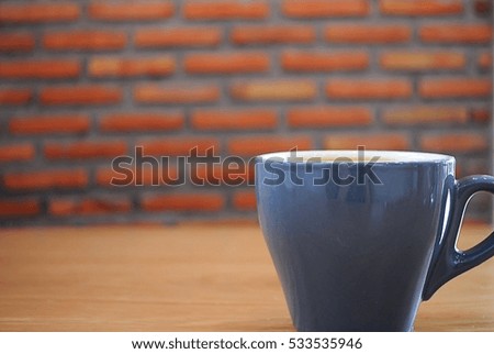 Coffee in a blue cup on a wooden table and brick background