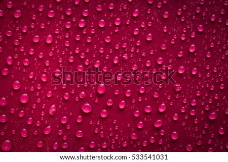 Drops of water on dark red surface. Macro photo, drop, shadow plastic base.