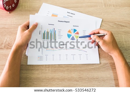 Business graphs & successful financial charts reports top view pointed by pen hold on male right hand for display, economic, presentation, finance, analysis, corporate, account and strategy concept.