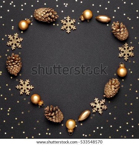 christmas or new year composition. heart shape frame made of christmas decoration and sparkles on blackboard background. holiday and celebration concept for postcard or invitation. flat lay. top view