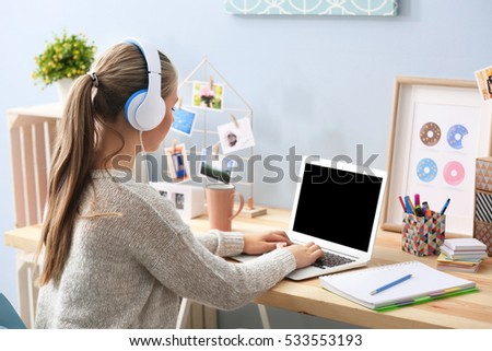 Cute teenager sitting at table and listening to music