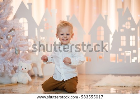 Little boy smiles on a background paper houses. White christmas. Selective focus