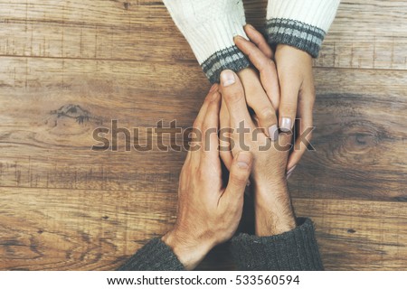 man and a woman holding hands at a wooden table Royalty-Free Stock Photo #533560594