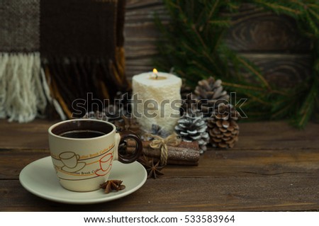 Christmas picture with a coffee on wooden background with blanket candle and a wreath of Christmas trees