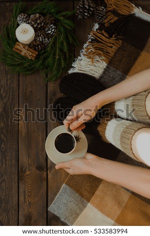 Christmas picture with a coffee on wooden background with blanket candle and a wreath of Christmas trees