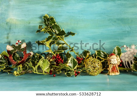A Christmas background with holly leaves, berries, and festive decorations, on a vibrant blue texture with garland lights and copyspace
