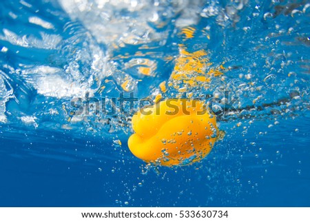 Bell pepper splashing in water on blue background
