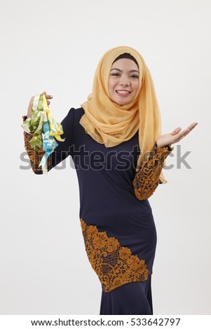 malay woman with tudung holding a bunch of ketupat