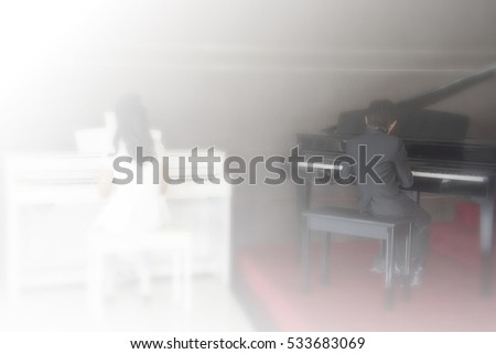 Blurred picture of girl musician playing white piano and boy playing black piano white and black tone background, concept of Ying Yang harmony