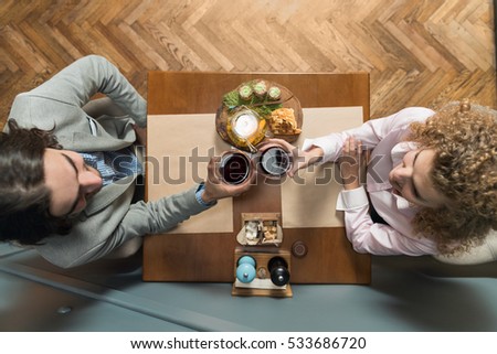Young Couple Drink Wine Sitting Restaurant Table, Romantic Date Man And Woman Hold Glasses Clink Toasting Top Angle View