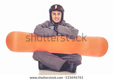 Handsome man in winter sport clothes is posing with a snowboard and smiling, isolated on white