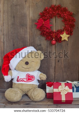 Teddy Bear wearing Santa Claus hat with Christmas Gift Boxes on wood background, concept Christmas