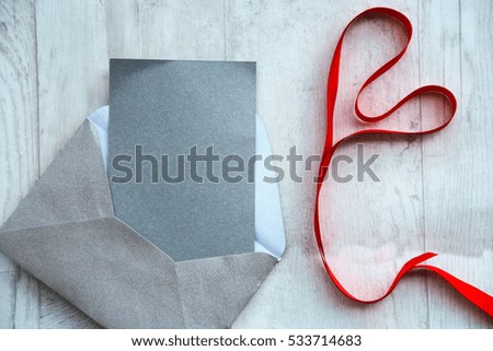romantic background ; blank card with a ribbon in shape of heart on a white wooden background 