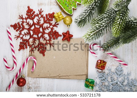 Christmas decoration and old paper on blue wooden table. Snowflakes, gifts, candies and fir branches on a wooden background.