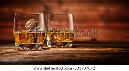 Two glasses of whiskey with ice cubes served on wooden planks. Vintage countertop with highlight and a glass of hard liquor Royalty-Free Stock Photo #533737072
