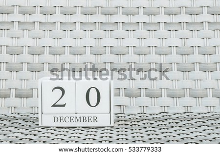 Closeup surface white wooden calendar with black 20 december word on blurred weave wood chair textured background with copy space , selective focus at the calendar