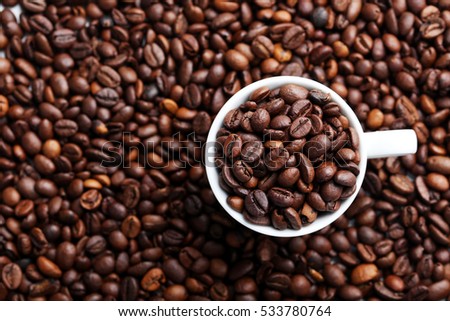 Brown roasted coffee beans in white cup