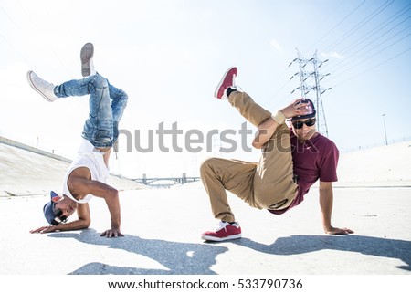 Two bboys ding some stunts - Street artist breakdancing outdoors Royalty-Free Stock Photo #533790736