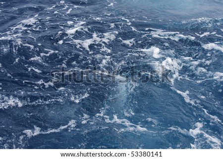 The wake of a boat cutting through the blue Mediterranean sea.