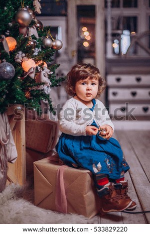 Happy little smiling girl with christmas gift box. Baby child near christmas tree lights open.