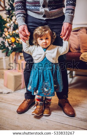 Portrait of affectionate family in christmas time. Family (mother, father, and little cute daughter) sitting near a Christmas tree and smiling face in the frame
