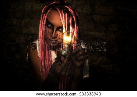 Girl with dreadlocks in the basement with a light bulb in his hands