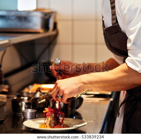 Preparing the chef for dinner. When the chef is pouring gravy on the food. Special touches by chef. Royalty-Free Stock Photo #533839234