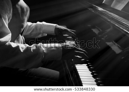 Afro American man hands playing piano in darkness Royalty-Free Stock Photo #533848330