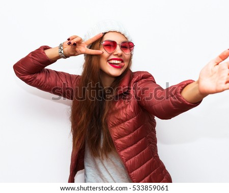 Taking picture. Smiling cheerful brunette-haired woman doing selfie on isolated white background.Smiling amazed young hipster girl making selfie photo isolated on white background