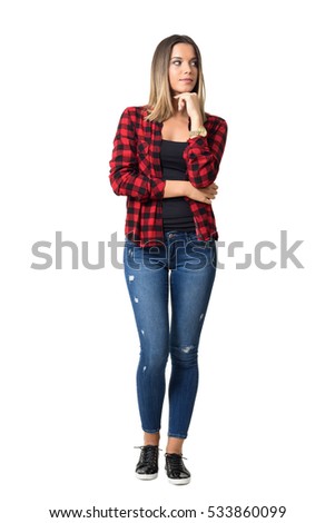 Sideway glance of gorgeous pensive young casual woman with hand on chin.  Full body length standing portrait isolated over white background. 